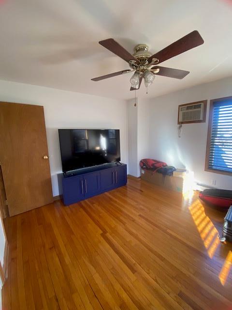 unfurnished living room featuring an AC wall unit and wood finished floors