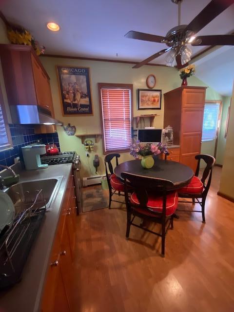 dining space with baseboard heating, light wood finished floors, and ceiling fan