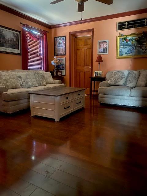 living room with dark wood finished floors, a ceiling fan, and ornamental molding