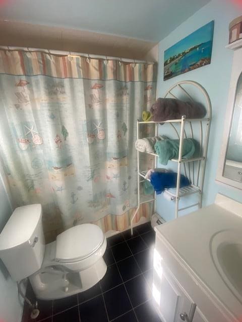 bathroom featuring tile patterned flooring, a shower with curtain, toilet, and vanity