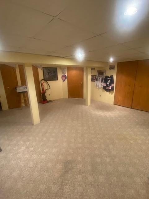 finished basement featuring a drop ceiling and carpet flooring