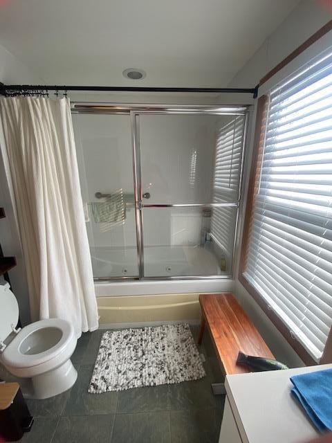 full bathroom featuring tile patterned floors, bath / shower combo with glass door, and toilet