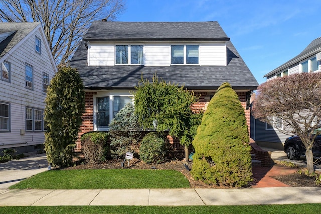 view of front of home featuring brick siding and roof with shingles