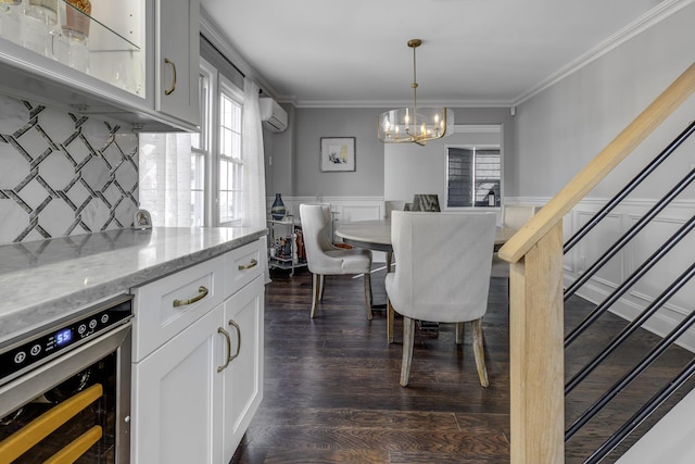 dining room featuring wine cooler, an inviting chandelier, ornamental molding, and wainscoting