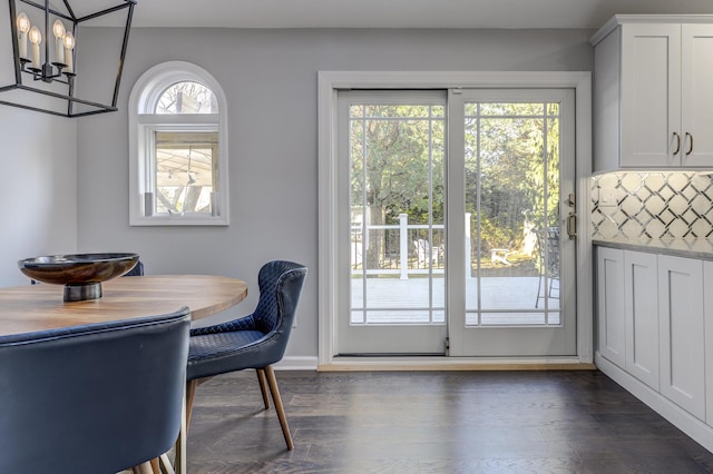 dining area featuring baseboards, dark wood-type flooring, and an inviting chandelier