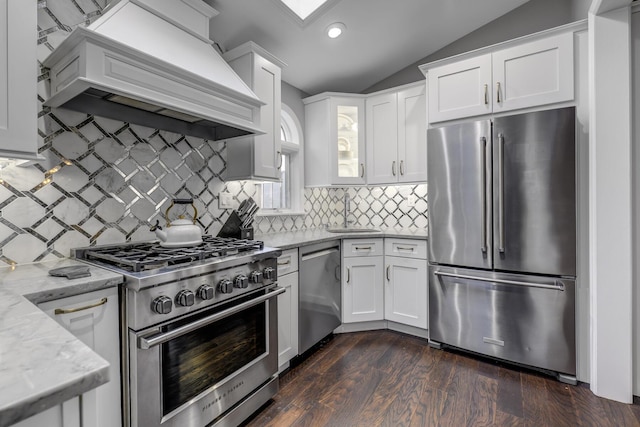 kitchen featuring a sink, premium appliances, white cabinetry, custom exhaust hood, and vaulted ceiling