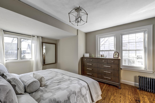 bedroom featuring dark wood-type flooring, radiator, baseboards, and a chandelier