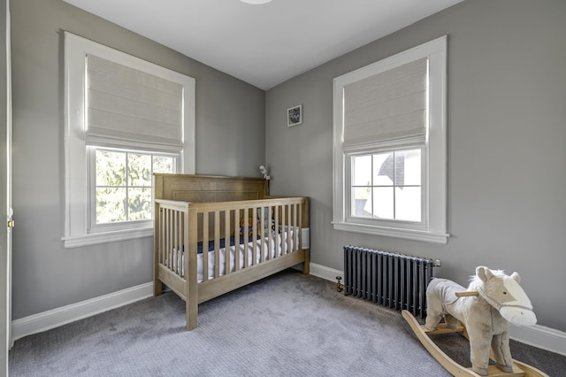 carpeted bedroom with a nursery area, radiator, and baseboards