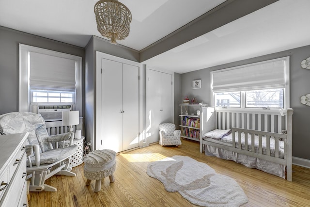 bedroom featuring multiple windows, cooling unit, baseboards, and wood finished floors