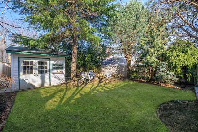 view of yard featuring a storage shed, an outdoor structure, and fence