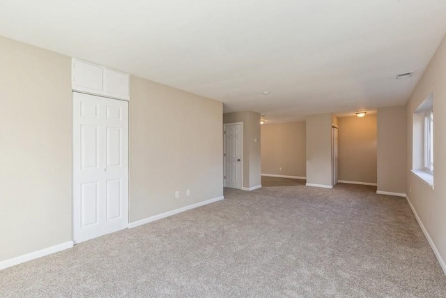 unfurnished room with baseboards, visible vents, and light colored carpet