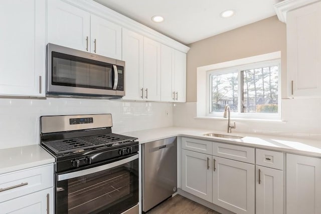 kitchen featuring white cabinets, stainless steel appliances, a sink, and light countertops