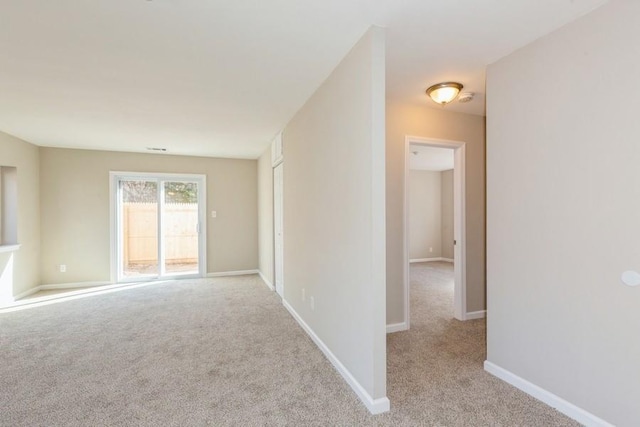 empty room featuring baseboards and light colored carpet