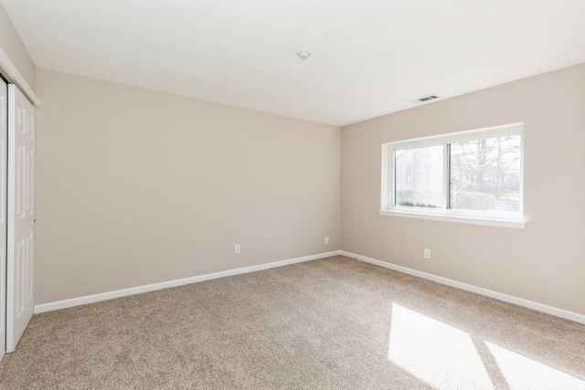 spare room with baseboards, visible vents, and light colored carpet