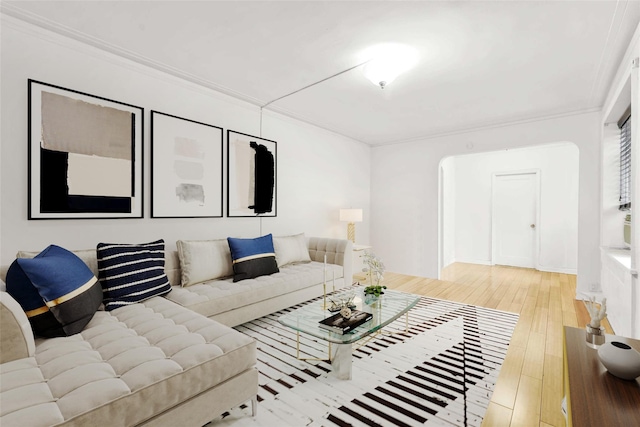 living room featuring arched walkways, wood-type flooring, and crown molding