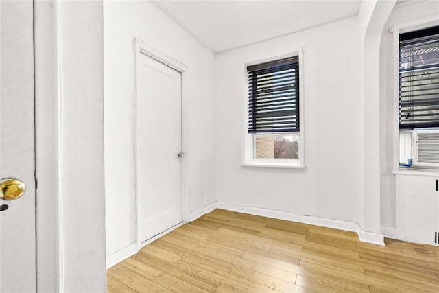 empty room with light wood-style floors, baseboards, and crown molding