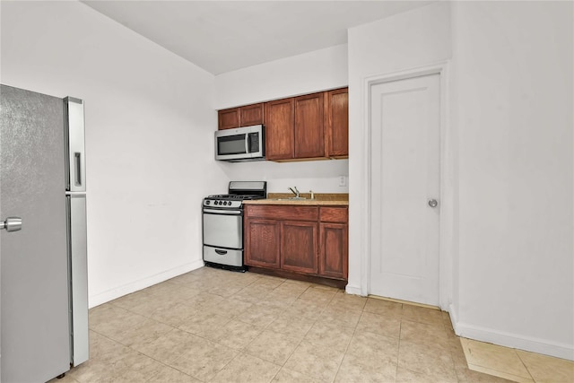 kitchen featuring stainless steel appliances, a sink, and baseboards