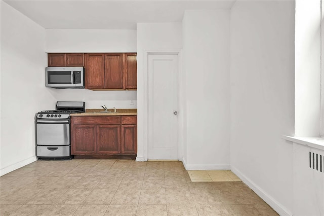 kitchen with stainless steel appliances, a sink, and baseboards