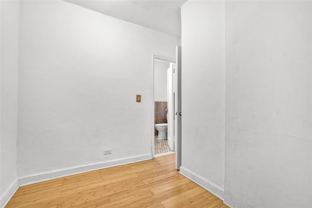 spare room with baseboards and hardwood / wood-style floors