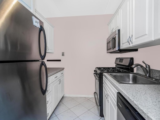 kitchen featuring stainless steel appliances, white cabinets, a sink, and light tile patterned flooring