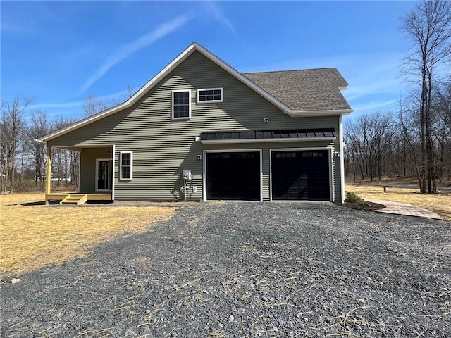 view of front of property with a garage, driveway, and roof with shingles