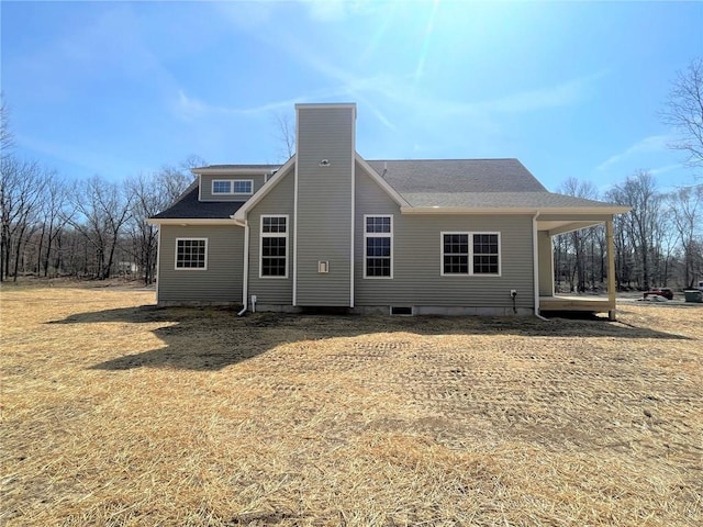 rear view of house with roof with shingles and a chimney