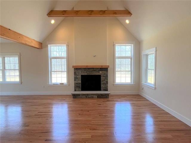 unfurnished living room featuring beamed ceiling, wood finished floors, and baseboards