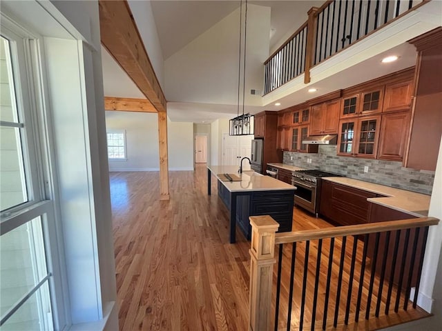 kitchen with light wood-style floors, brown cabinets, stainless steel appliances, light countertops, and under cabinet range hood