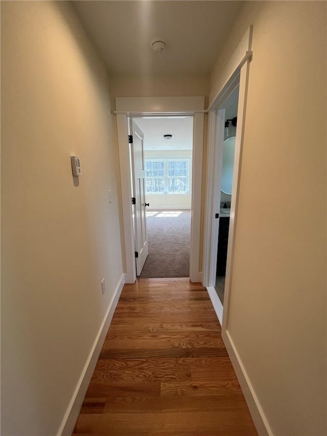 corridor featuring baseboards and wood finished floors