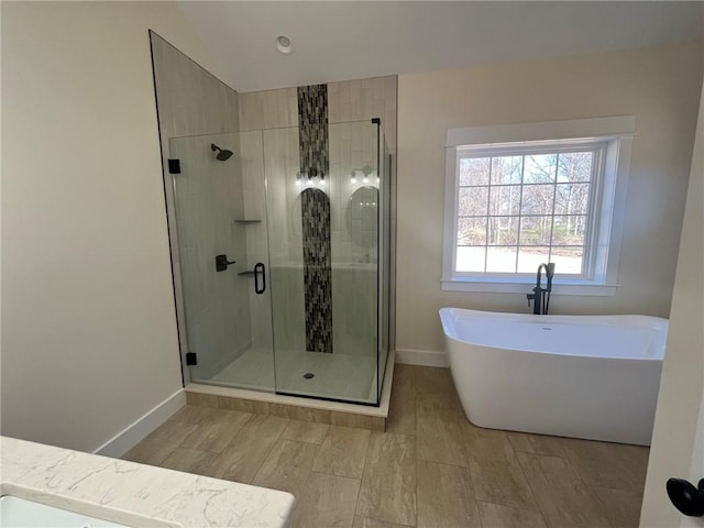 full bath featuring a freestanding bath, a stall shower, lofted ceiling, and baseboards