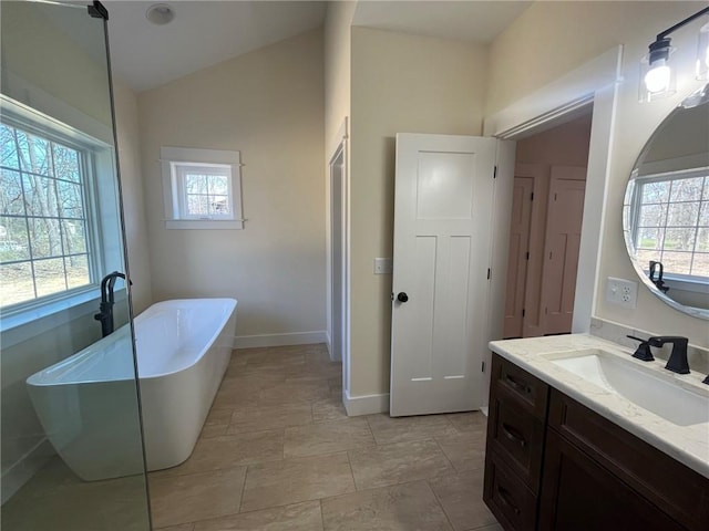 full bath with a freestanding tub, vaulted ceiling, vanity, and baseboards