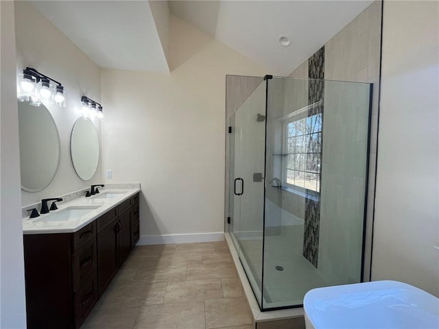 bathroom featuring lofted ceiling, a stall shower, baseboards, and a sink