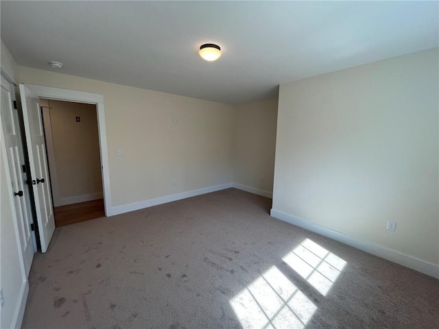 spare room with light colored carpet and baseboards