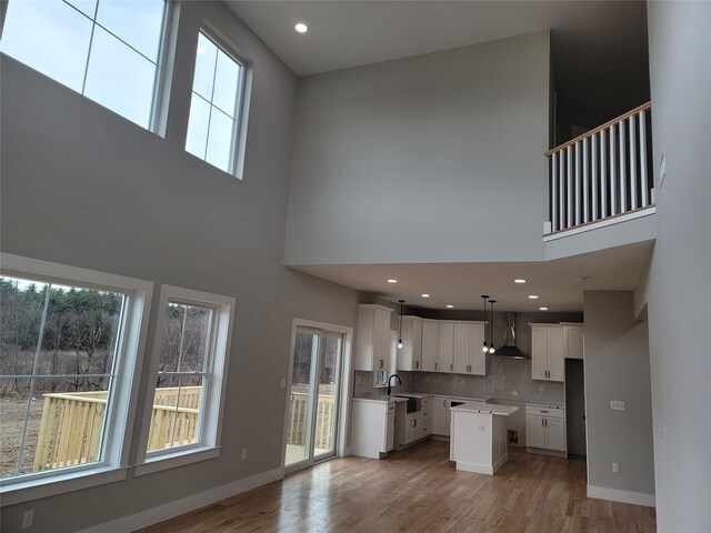 472 Wheeler Rd, Florida, NY 10921 - unfurnished living room with light wood-style floors, a sink, baseboards, and a towering ceiling