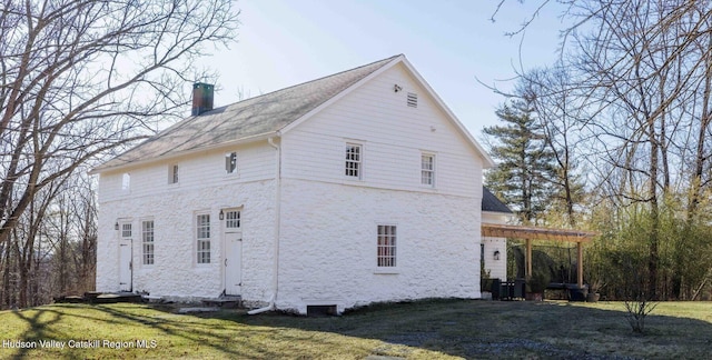 view of side of home featuring a yard, a chimney, and entry steps