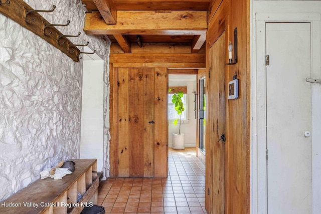 corridor with light tile patterned floors and beam ceiling