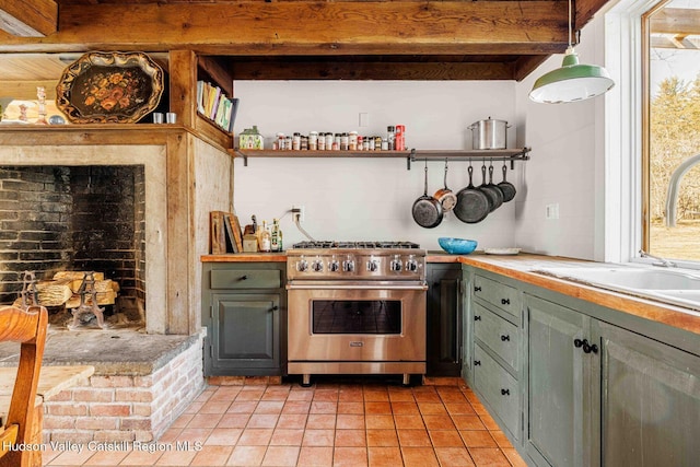 kitchen featuring beamed ceiling, green cabinets, high end stainless steel range, and a sink