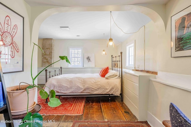 bedroom featuring hardwood / wood-style flooring, arched walkways, and visible vents