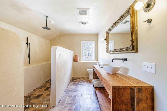 full bath with visible vents, toilet, walk in shower, and stone tile floors