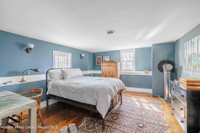 bedroom featuring light wood finished floors, visible vents, and baseboards