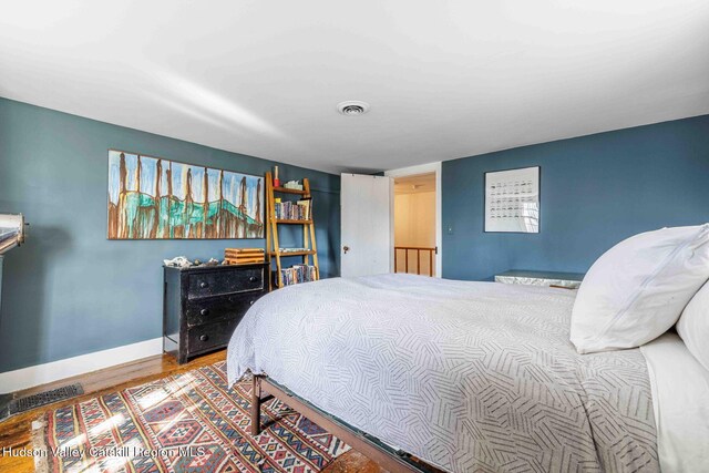 bedroom featuring wood finished floors, visible vents, and baseboards