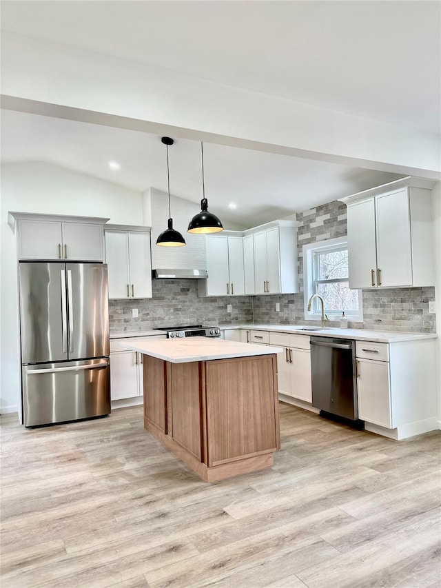 kitchen with stainless steel appliances, light countertops, vaulted ceiling, and light wood finished floors