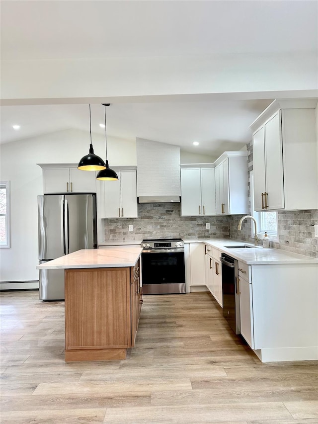 kitchen featuring stainless steel appliances, a baseboard radiator, lofted ceiling, a sink, and wall chimney range hood