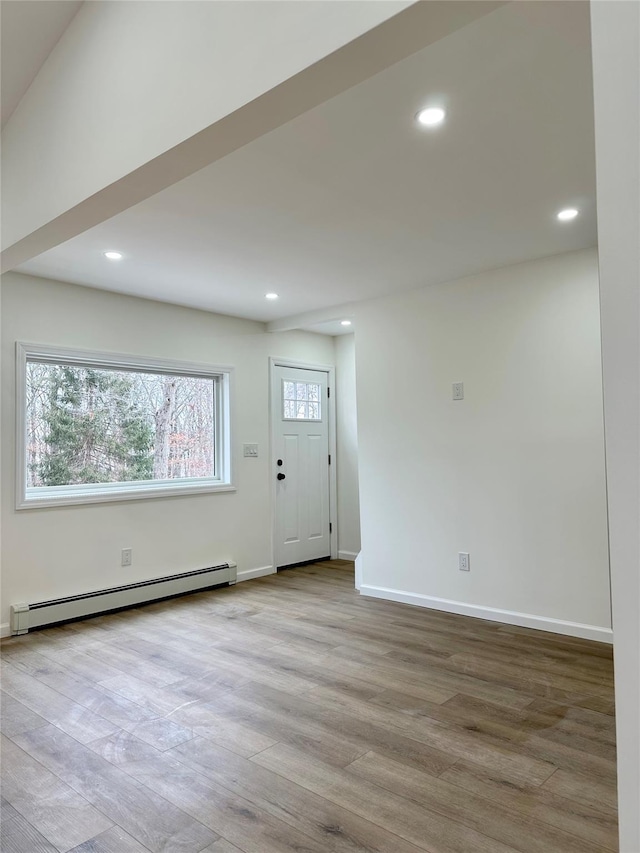 empty room featuring a baseboard heating unit, recessed lighting, wood finished floors, and baseboards