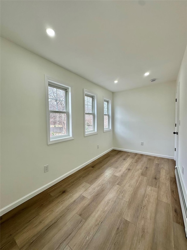 unfurnished room with a baseboard radiator, baseboards, wood finished floors, and recessed lighting