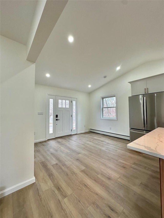 unfurnished living room with a baseboard radiator, recessed lighting, light wood-style flooring, vaulted ceiling, and baseboards