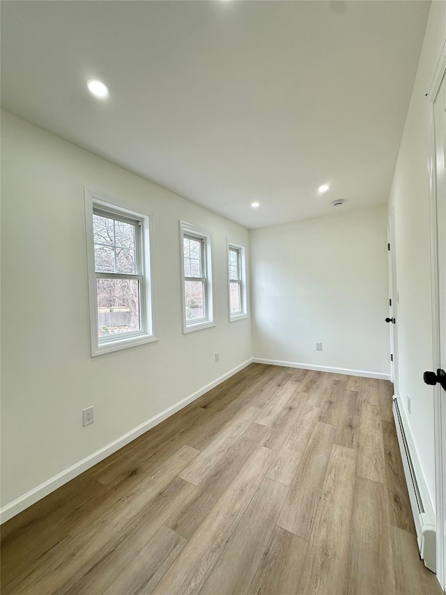 unfurnished room featuring a baseboard radiator, baseboards, light wood-style flooring, and recessed lighting