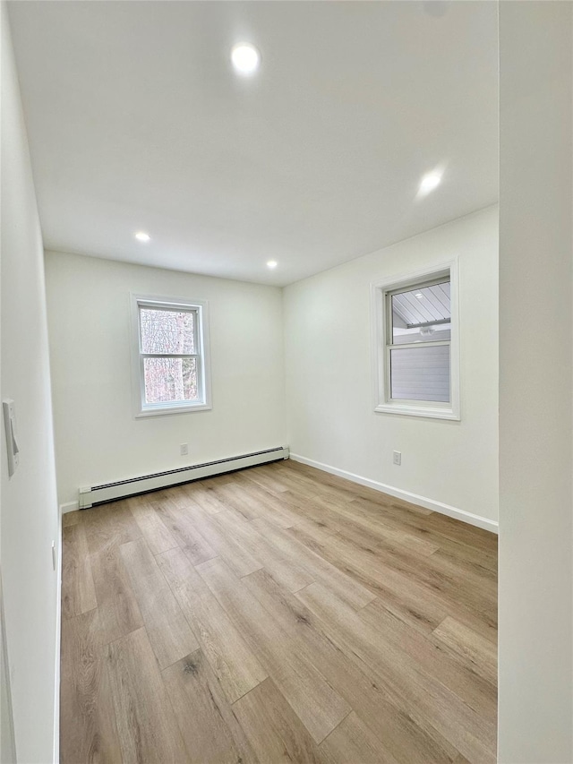 unfurnished room featuring a baseboard heating unit, recessed lighting, light wood-type flooring, and baseboards