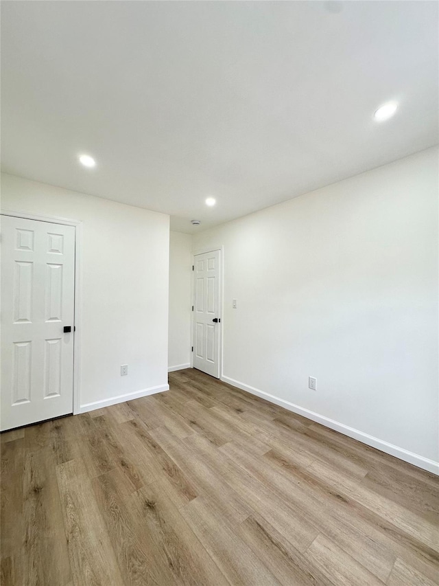 empty room with recessed lighting, wood finished floors, and baseboards