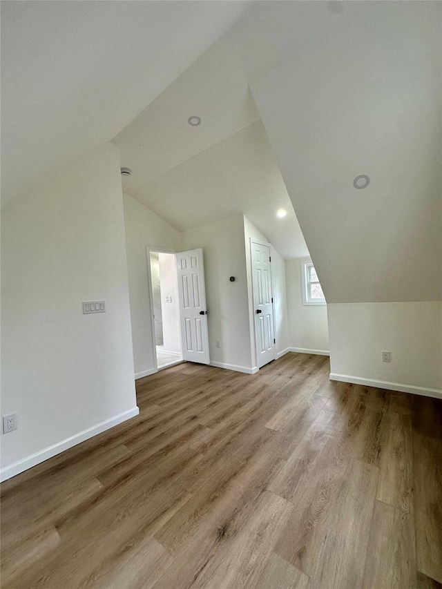 additional living space with baseboards, vaulted ceiling, wood finished floors, and recessed lighting